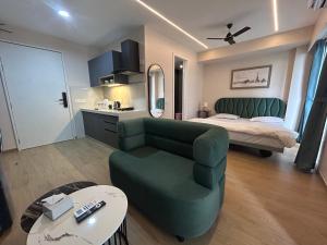 a living room with a green chair and a bed at UHomes Pune airport in Pune