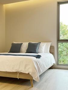 a bedroom with a large bed with two windows at Peace Nakhon Nayok in Nakhon Nayok