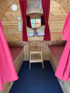 a room with two beds in a cabin with red curtains at Campingresort Hinterstoder in Hinterstoder
