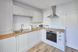 a white kitchen with white cabinets and a sink at 94 Roseberry Cottage in the market town of Guisborough in Guisborough