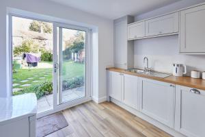 a kitchen with white cabinets and a large window at 94 Roseberry Cottage in the market town of Guisborough in Guisborough +6 photos