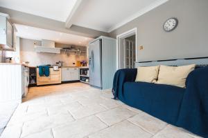 a living room with a blue couch and a kitchen at Lavender Cottage in Burley