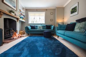 a living room with two blue couches and a fireplace at Lavender Cottage in Burley