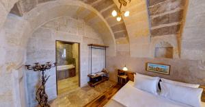 1 dormitorio con 1 cama blanca en una pared de piedra en Ages in Cappadocia Premium, en Uchisar 62 fotos más