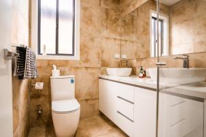 a bathroom with a toilet and a sink and a mirror at Charming Deanside Home with Cosy Vibes in Caroline Springs +36 photos