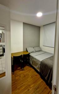 a bedroom with a bed and a desk and a table at Studio aconchegante e funcional in Sao Paulo