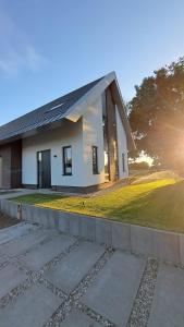 una piccola casa bianca con il sole dietro. di Vakantiewoning OpdeBaan a Kaatsheuvel