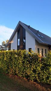 una casa bianca con un tetto nero dietro una siepe di Vakantiewoning OpdeBaan a Kaatsheuvel