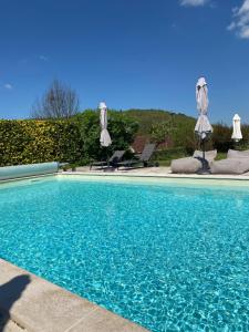 a swimming pool with blue water and umbrellas at La SAURA in Lusigny-sur-Ouche