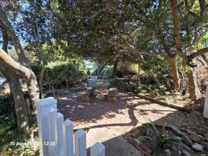 ein weißer Lattenzaun in einem Park mit einer Bank in der Unterkunft The Genet Cottage in Reebok