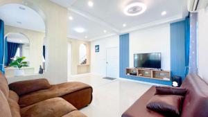 a living room with a couch and a tv at บ้านย่าพลูวิลล่าพลาบ้านฉางระยอง in Ban Phala