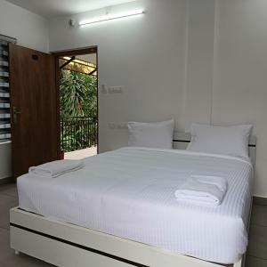 Una cama blanca en una habitación con ventana. en Hotel Eleven Space Kochi, en Kochi