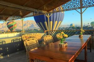 a wooden table and chairs on a balcony with mountains at Holiday Dream Of Luxor in Luxor