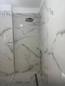 une salle de bains avec douche et murs en marbre dans l'établissement Florida apartments, à Golem