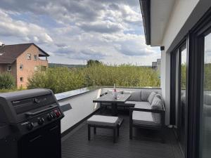 balcón con sofá, mesa y parrilla en Die Stadtvilla, en Holzminden
