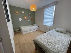 Un dormitorio con dos camas y una ventana. en Cocon d'Aurore, en La Baule