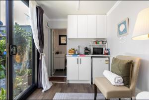 a small kitchen with white cabinets and a chair at Tiny Home Beach Serenity! in Sydney