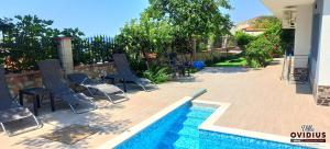 a group of chairs sitting next to a swimming pool at Arode Villa Ovidius in Balchik