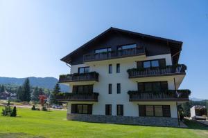 a tall white building with a black roof at Cara Grand Chalet in Braşov