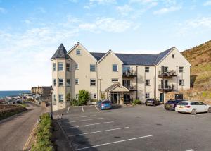 ein großes Gebäude mit auf einem Parkplatz abgestellten Autos in der Unterkunft Beachcombers in Newquay Bay Resort