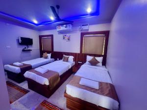 a room with three beds with blue lights on it at Hotel Pramod Park in Nūāhatā