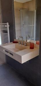 a bathroom sink with two faucets and a mirror at La Macarena Suites in Villa General Belgrano