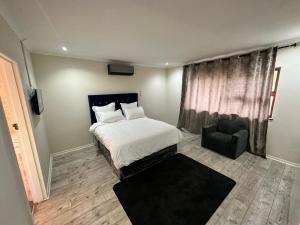 a bedroom with a white bed and a chair at Joy House in Cape Town