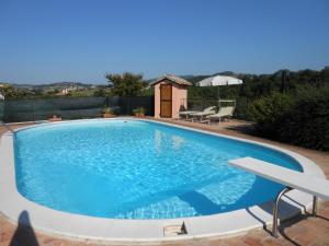 a large blue swimming pool with two chairs and a table at Tre Archi in Cagli