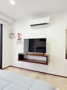 a bedroom with a tv on a white wall at NEW Luxury Modern Condo by Menesse in Playa del Carmen +29 photos