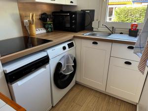 a kitchen with a washing machine and a sink at Maisonnette au calme, T3, 6 pers résidence avec piscine et wifi privée proche lac et océan in Soustons