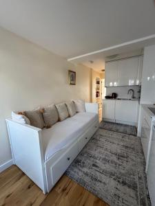 a white couch in a living room with a kitchen at Sela House - Luton Airport in Luton