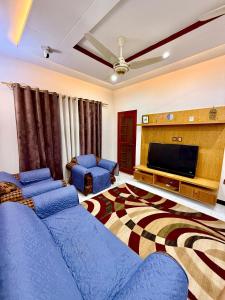 a living room with blue couches and a flat screen tv at Bahria Town Karachi Full Furnished Guests Houses in Karachi