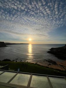 a view of the ocean with the sun setting over the water at Ensenada Dichosa in Suances +9 photos