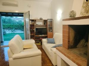 a living room with two white chairs and a fireplace at Bougainville Bianco in Quartu SantʼElena