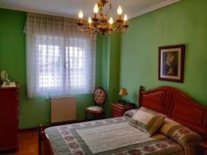 a green bedroom with a bed and a chandelier at Precioso apartamento en el Paraíso Natural 