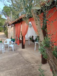Un patio al aire libre con cortinas y mesas naranjas y un árbol. en Oasi di san Benedetto, en Castellaneta