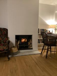 a living room with a fireplace with a chair and a table at Riverside country cottage in Newhaven