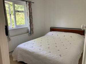 Una cama blanca en un dormitorio con ventana. en Riverside country cottage, en Newhaven
