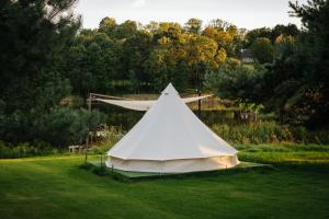 a white tent sitting on a field of grass at Lakeside camping in Balninkai