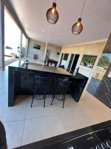 une grande cuisine avec un comptoir noir et des chaises dans l'établissement Rancho Fiel - Lago das Brisas, à Burity Alegre
