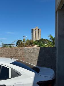 une voiture blanche garée à côté d'un mur avec un grand bâtiment dans l'établissement Rancho Fiel - Lago das Brisas, à Burity Alegre