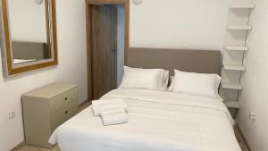 a bedroom with a bed with white sheets and a mirror at Rhodes Beach Side Houses in Ixia