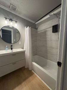 Un baño con bañera, lavabo y espejo. en Cozy Stay 5 Min Ft Hood, en Killeen