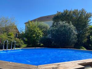 a large blue swimming pool in front of a house at Le Nid'Ophé Studio Cosy - Proche Disneyland Paris in Mareuil-lès-Meaux