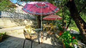 a patio with a table and chairs and an umbrella at Villa Gabliani in Mestia