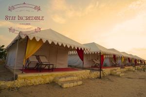 Una hilera de tiendas de campaña con sillas en una playa. en Stay Incredible Camp, en Sām