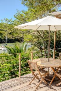 une table et une chaise en bois avec un parasol sur une terrasse dans l'établissement EvaZion, à Grande Rivière Sud Est