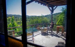 a woman sitting in a chair on the balcony of a house at Casa Zíngara Alucinante Casa de Ensueño en las Sierras in Salsipuedes