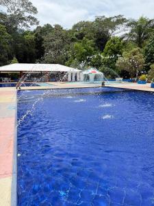 a large pool of blue water with a fountain at Eco hotel el bosque in Doradal +94 photos