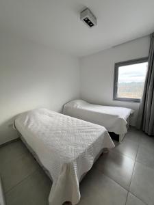 Dos camas en una habitación con ventana. en Torres al mar, en Monte Hermoso